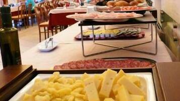 Un buffet con diverse pietanze, tra cui carni, formaggi e altri piatti.