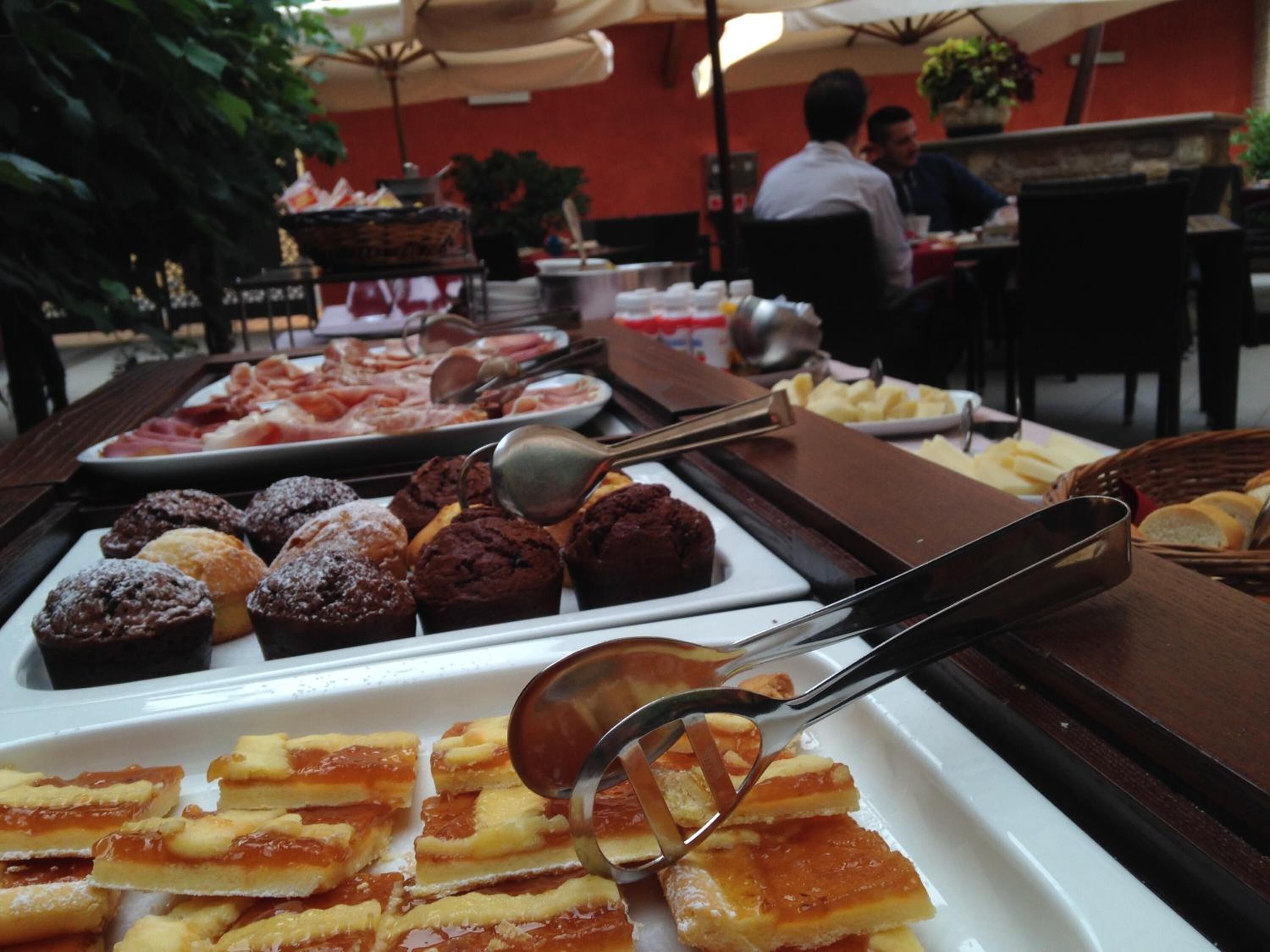 A buffet with various desserts and pastries, including brownies and macarons, with serving utensils.