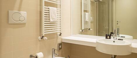 A modern bathroom with a bidet, two sinks, a mirror, and towel racks.