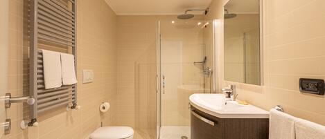A modern bathroom with a shower, toilet, bidet, and a large mirror.