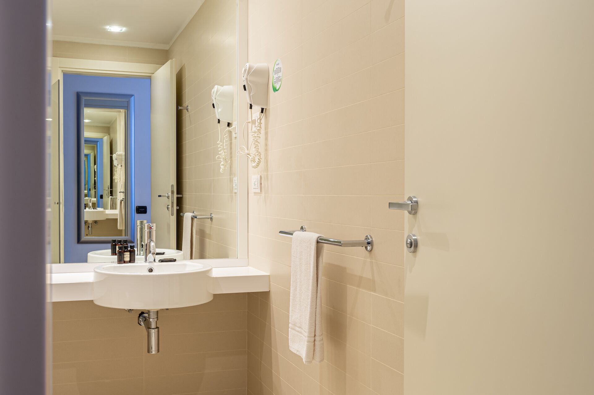 A bathroom with a sink, mirror, and towel rack.