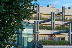 Un edificio moderno con ascensor de vidrio, barandillas de metal y techo plano.