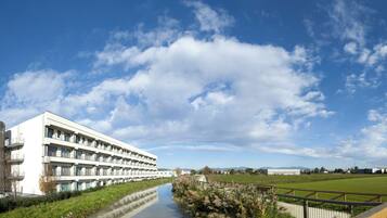 Un bâtiment moderne doté de nombreux balcons, avec une rivière en contrebas et un ciel bleu dégagé.