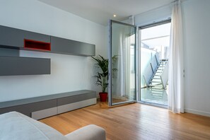 A modern living room with a built-in bench, a potted plant, and a sliding glass door leading to a staircase. - UNA Hotels Le Terrazze Treviso Hotel & Residence (Villorba)