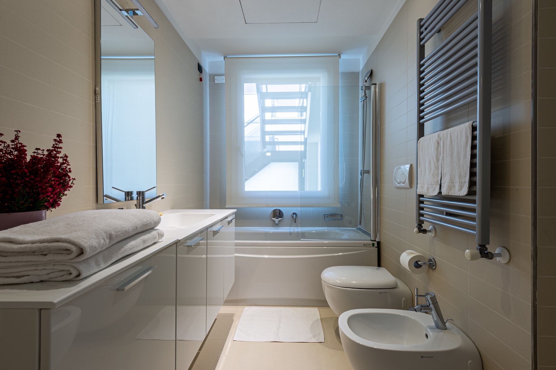 Une salle de bain moderne équipée d’une baignoire, de toilettes, d’un bidet et d’un grand miroir.