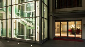 Un bâtiment moderne doté d’une façade en verre, d’un escalier et d’un espace d’accueil agrémenté de plantes.