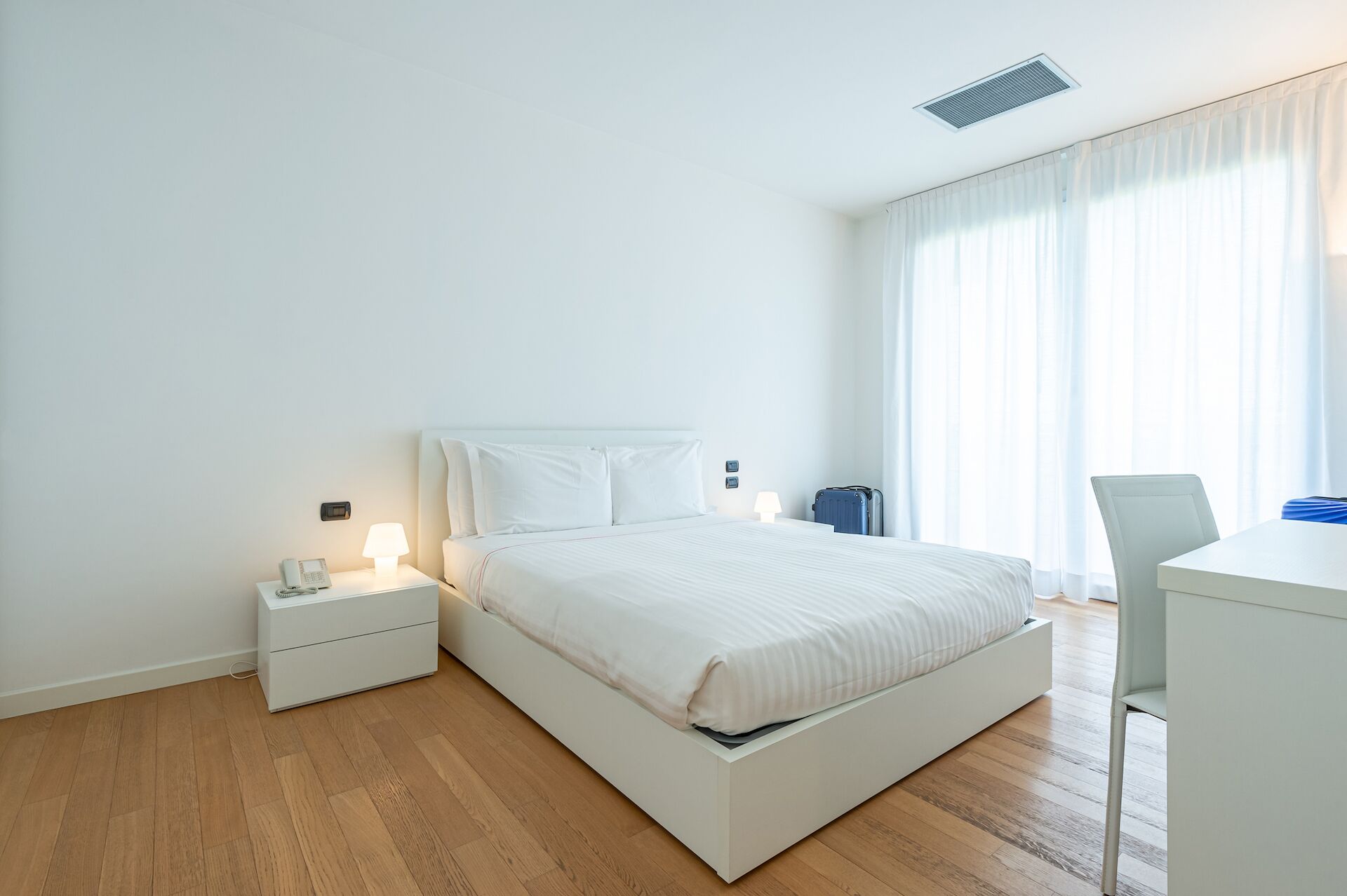 Habitació d'hotel moderna amb llit, taules de nit, escriptori i cadira.