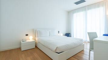 Una habitación de hotel moderna con cama, mesitas de noche, escritorio y una silla.