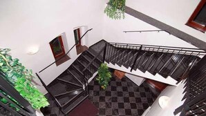Un interior de varios niveles con suelo a cuadros, barandillas negras y una escalera.