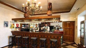 Una zona de bar con taburetes, una barra y una lámpara de araña.