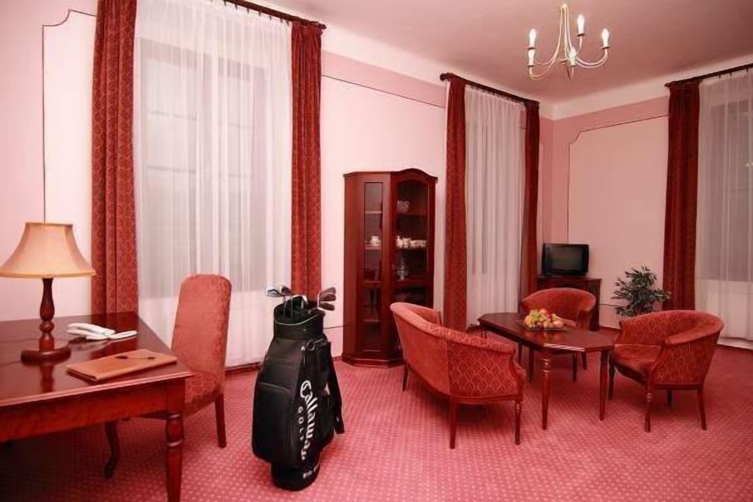 Ein Hotelzimmer mit einem Holztisch, einem Stuhl, einer Golfbag, einem Fernseher und einem Schrank.