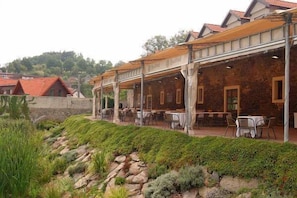A restaurant with outdoor seating, stone walls, and a hillside backdrop. - Golf Resort Hotel Konopiste (Bystrice)