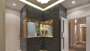 A corner room with a stone accent wall, a mirror, and a vase with flowers.