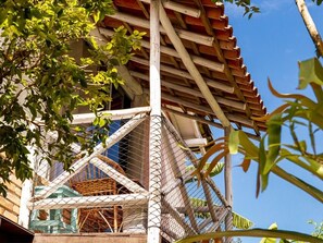 A traditional wooden structure with a thatched roof, surrounded by a wire mesh enclosure, and a woven basket visible inside. - Pousada Recanto da Villa (Ilhabela)
