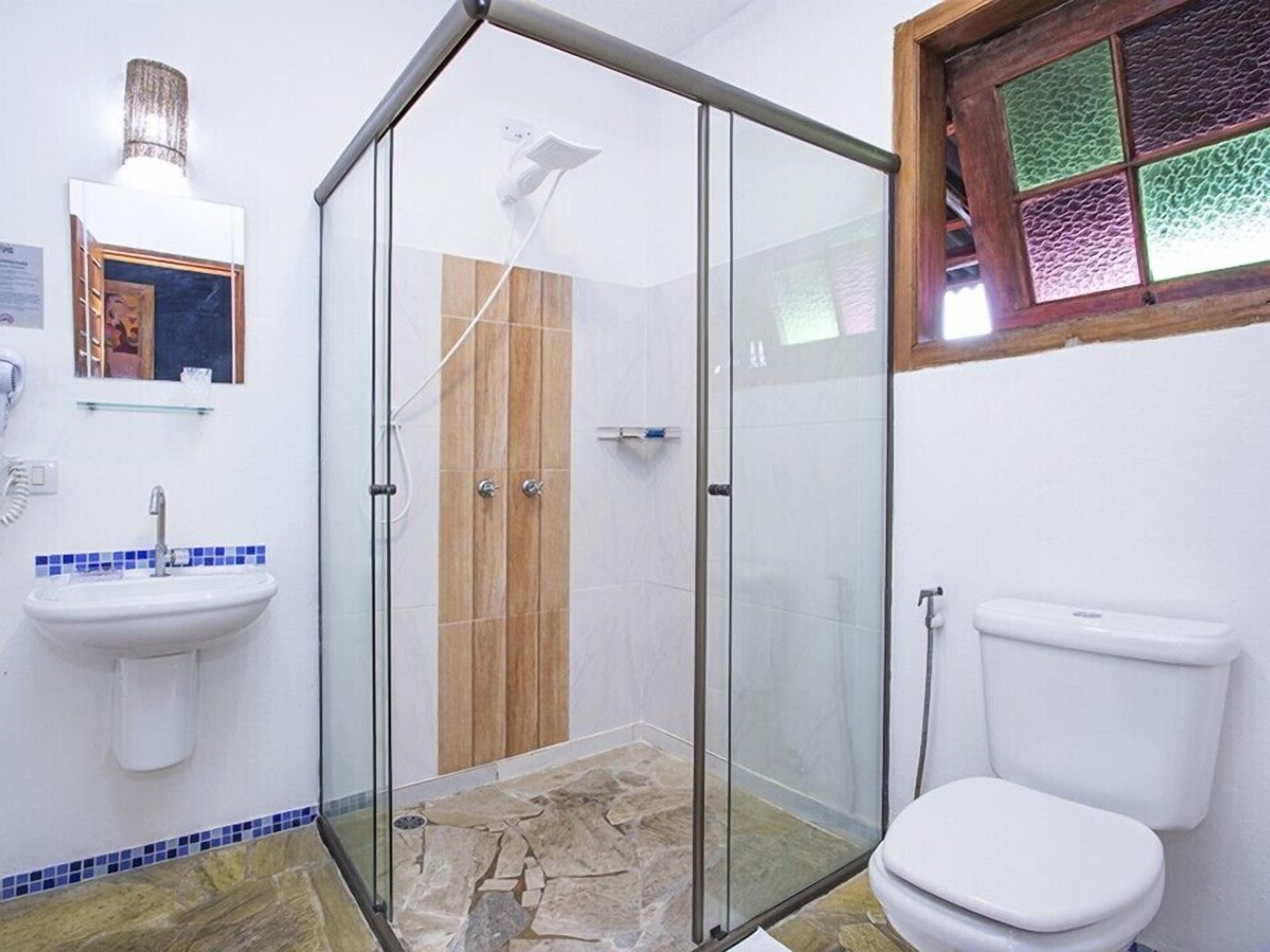 Un baño con cabina de ducha de vidrio, un lavabo blanco con azulejos azules y un inodoro.