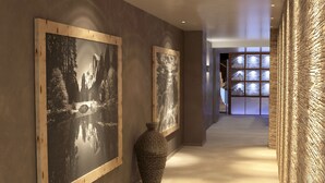 A hallway with two framed black and white photographs on the walls, a textured vase, and a wooden floor. - Hotel La Torretta (Vermiglio)
