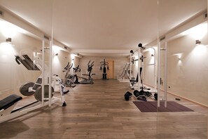 A modern gym with cardio machines, free weights, and a mirror wall. - Hotel La Torretta (Vermiglio)
