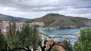 Un pueblo costero con un puerto deportivo, edificios y colinas al fondo.