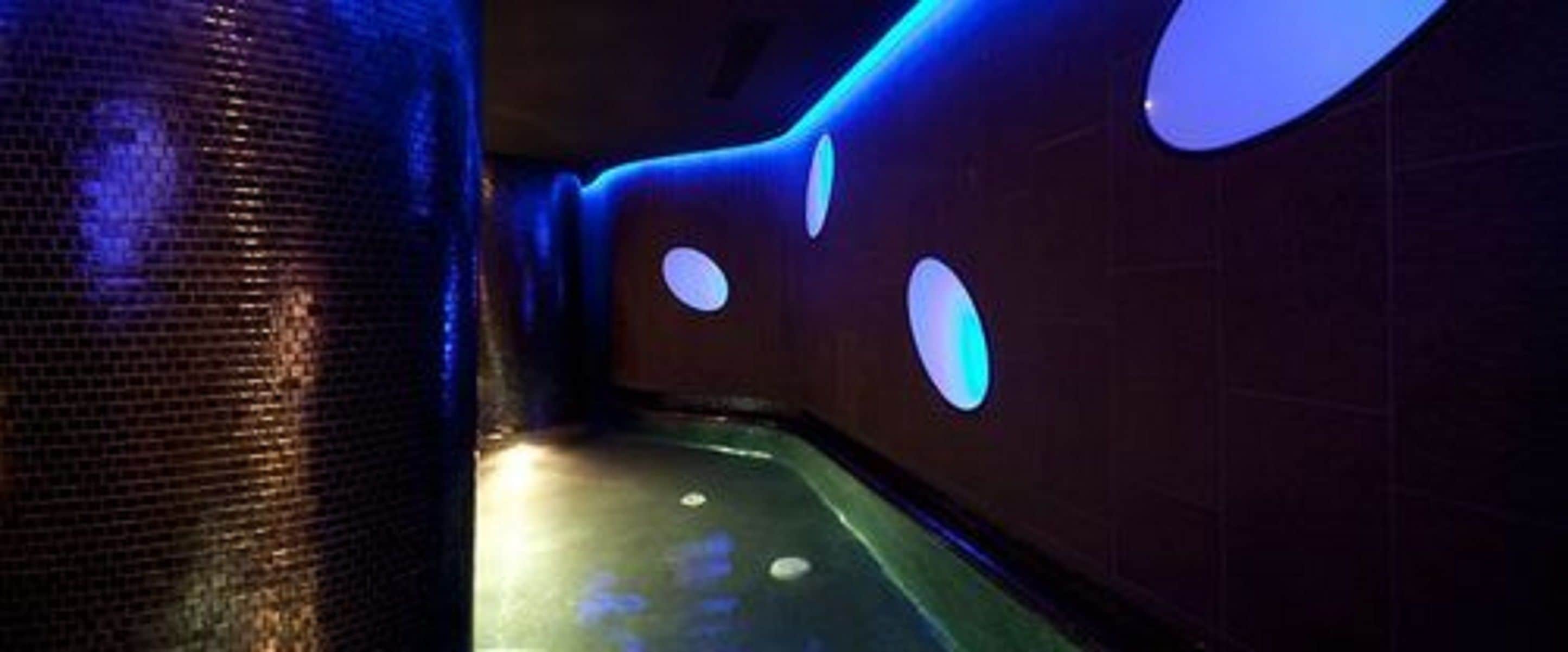 A dimly lit hallway with a textured wall and circular light fixtures.