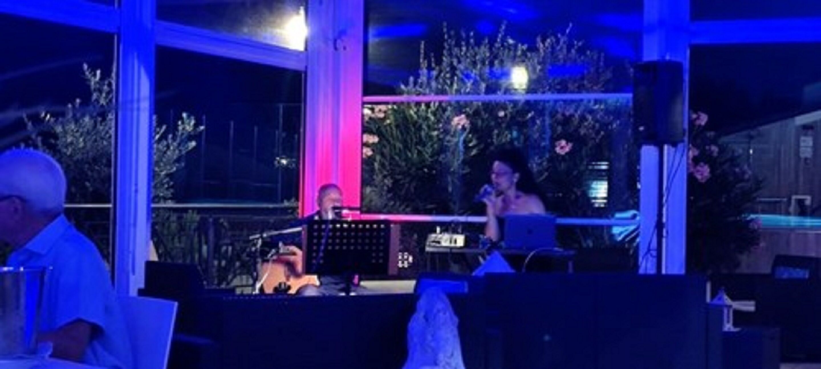 An indoor venue with a stage, seating area, and large windows.