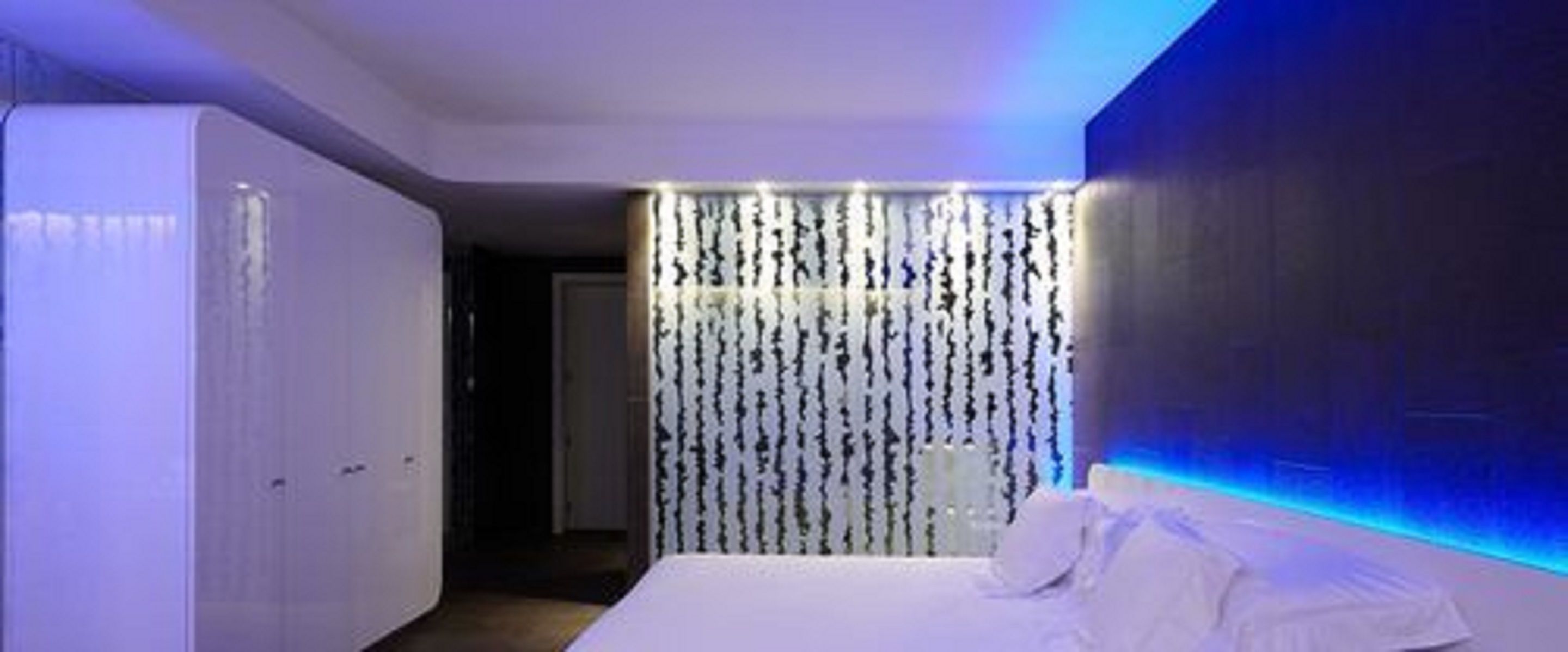Una habitación de hotel moderna con una cama, un armario y una pared con líneas verticales.