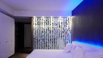 Una habitación de hotel moderna con una cama, un armario y una pared con líneas verticales.