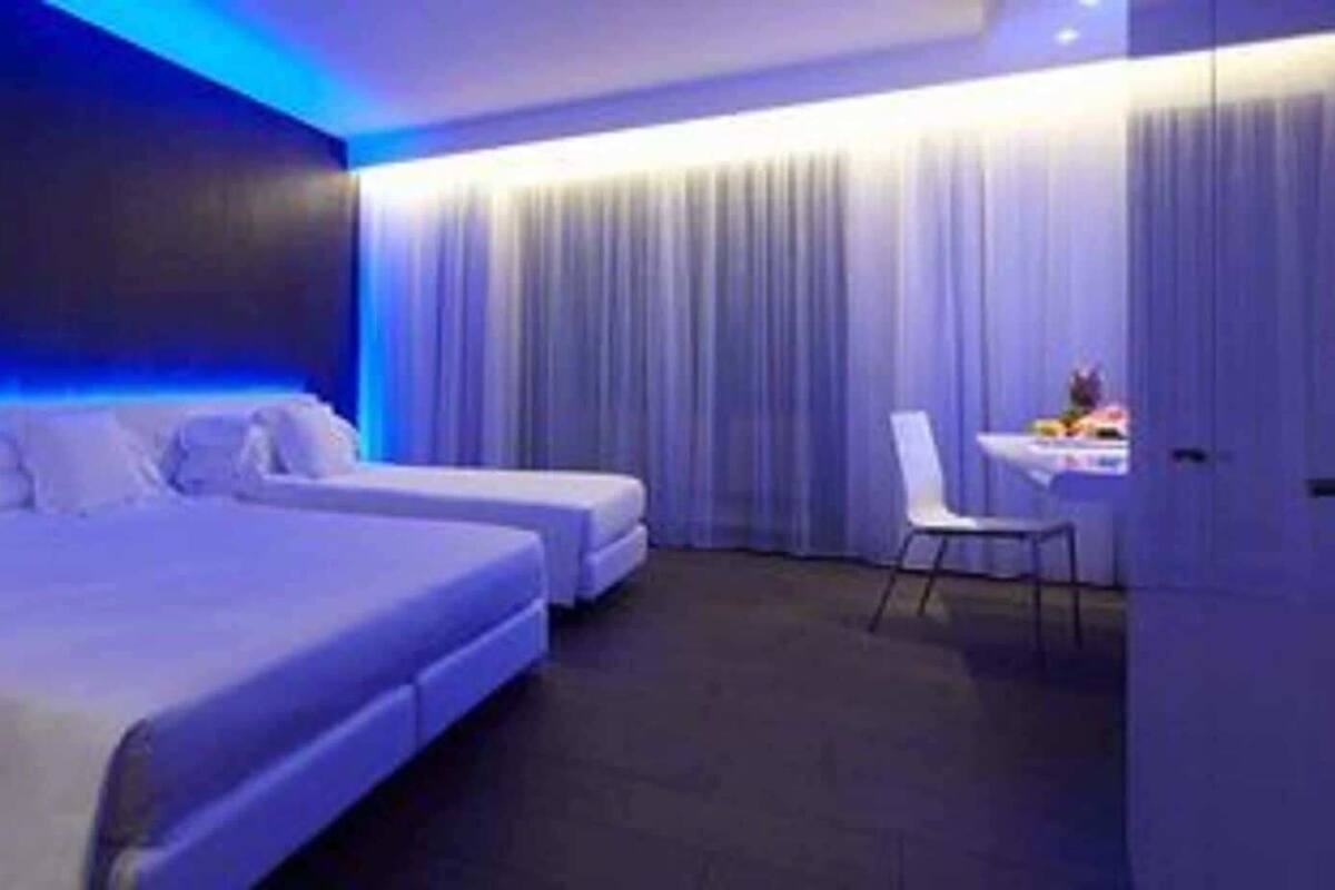 Une chambre d’hôtel moderne équipée d’un grand lit, d’un lit plus petit, d’un bureau et d’une chaise.