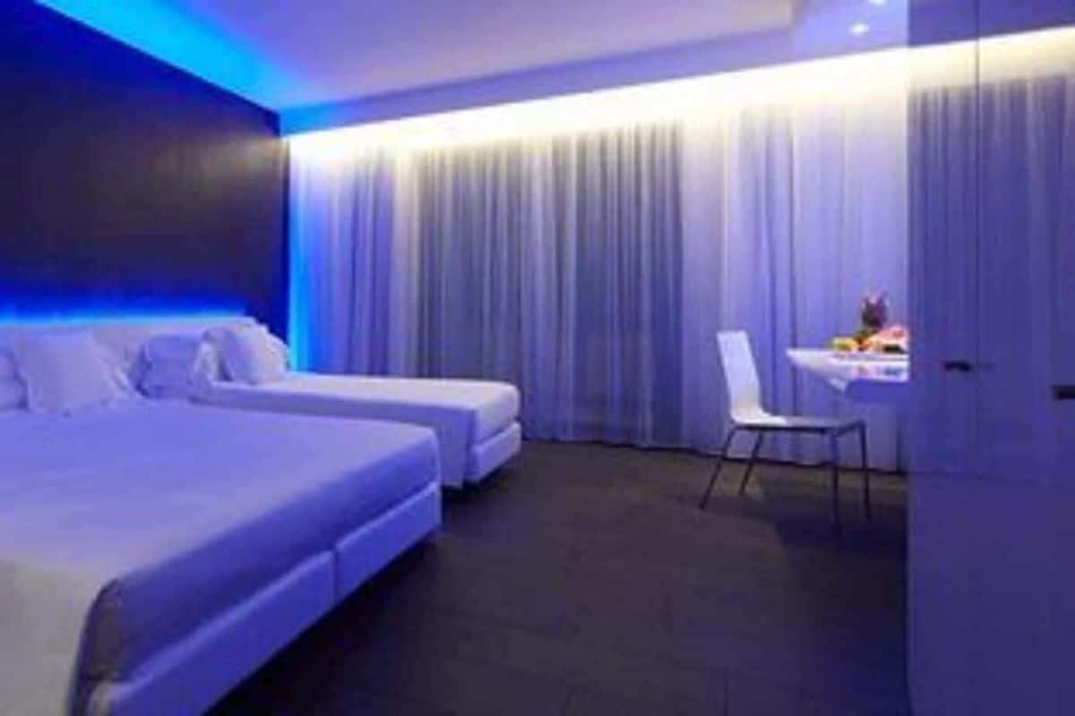 Une chambre d’hôtel moderne équipée d’un grand lit, d’un lit plus petit, d’un bureau et d’une chaise.