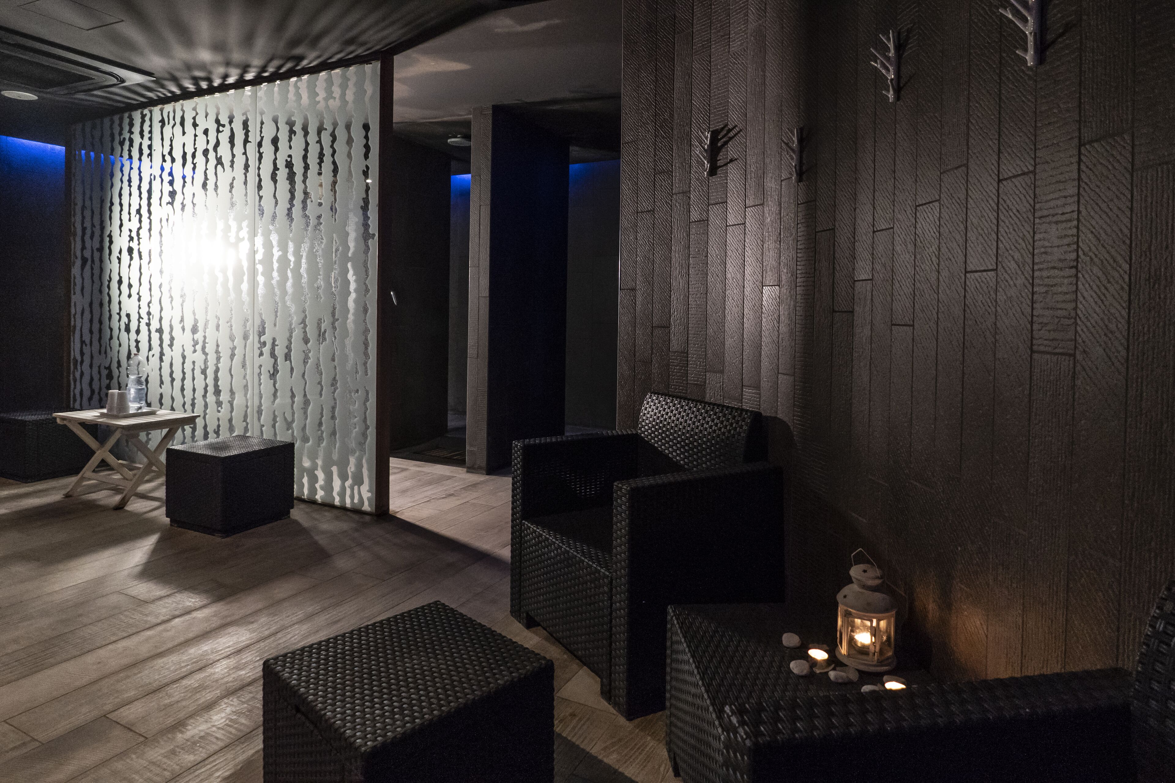 Un espacio lounge moderno con mobiliario de mimbre, una mesita y un farol decorativo.