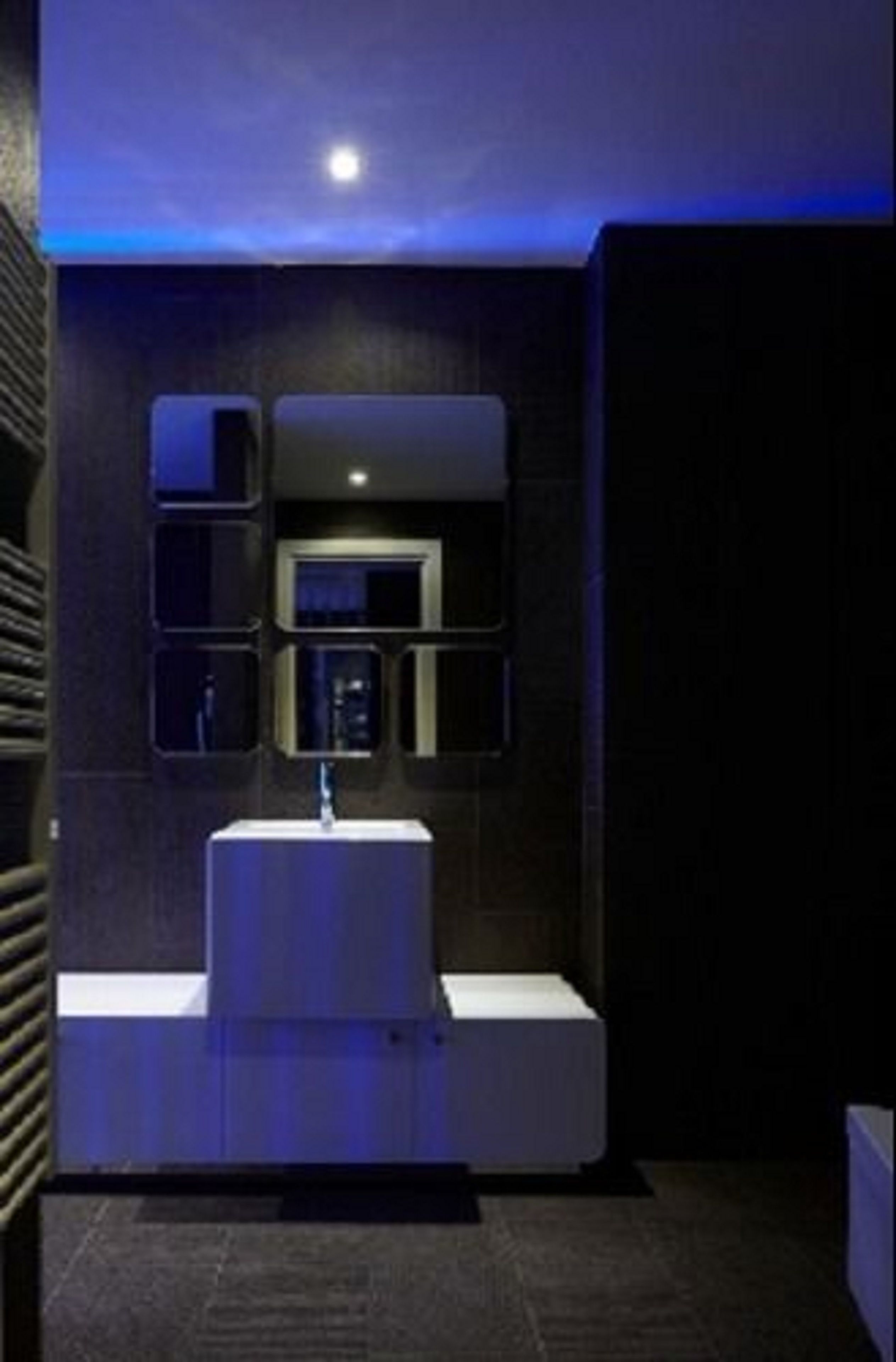 Uma casa de banho moderna com uma pia branca, um espelho e um candeeiro fixado na parede.