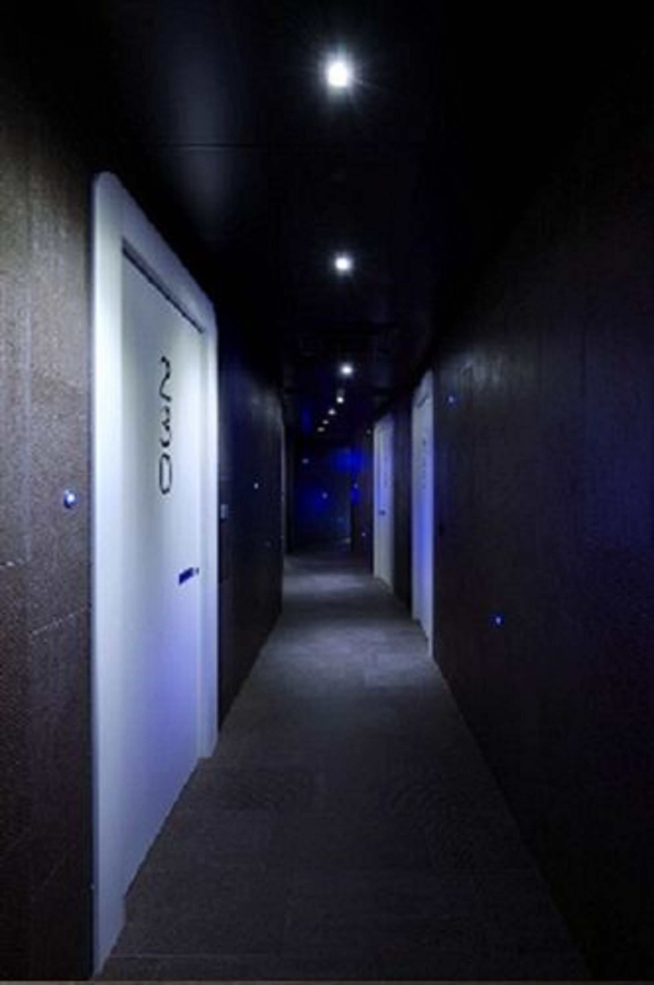 Un corridoio stretto con porte su un lato, che conduce a camere individuali.
