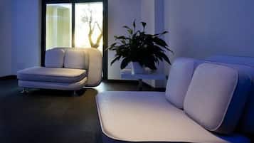 Uma sala de estar moderna com sofá, poltrona, uma planta em vaso e vista através de uma porta de vidro.
