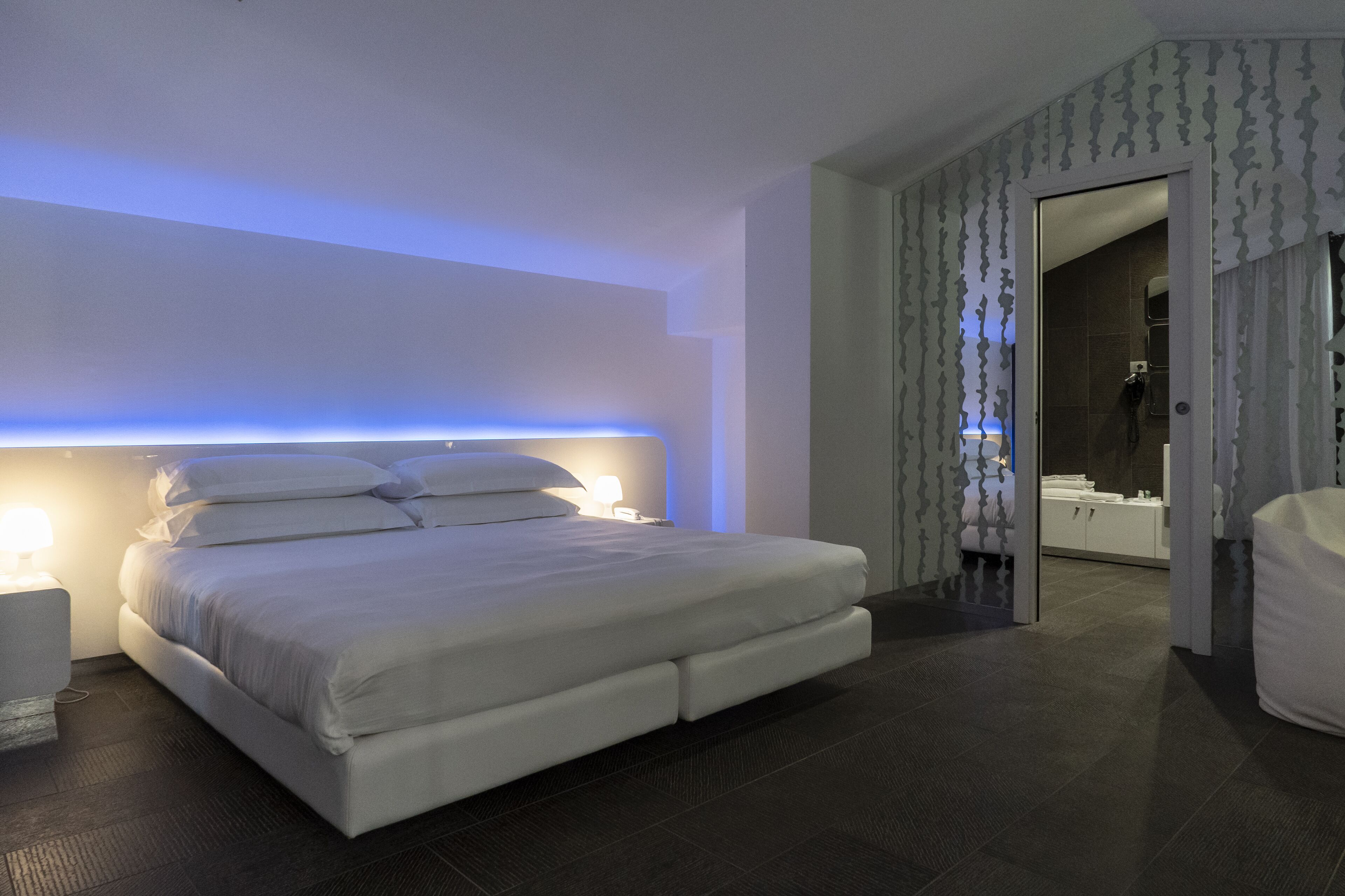 Quarto moderno com cama grande, luminárias de cabeceira e closet espaçoso.