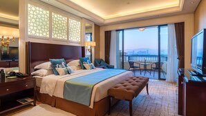 A hotel room with a large bed, a desk with a phone, a TV, and a balcony with a city view. - Yourworld International Conference Center (Jinhua)