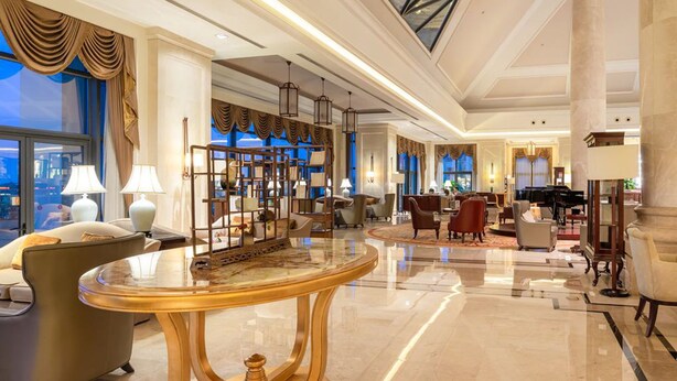 A spacious lobby with a high ceiling, a grand piano, and a large window offering a city view. - Yourworld International Conference Center (Jinhua)