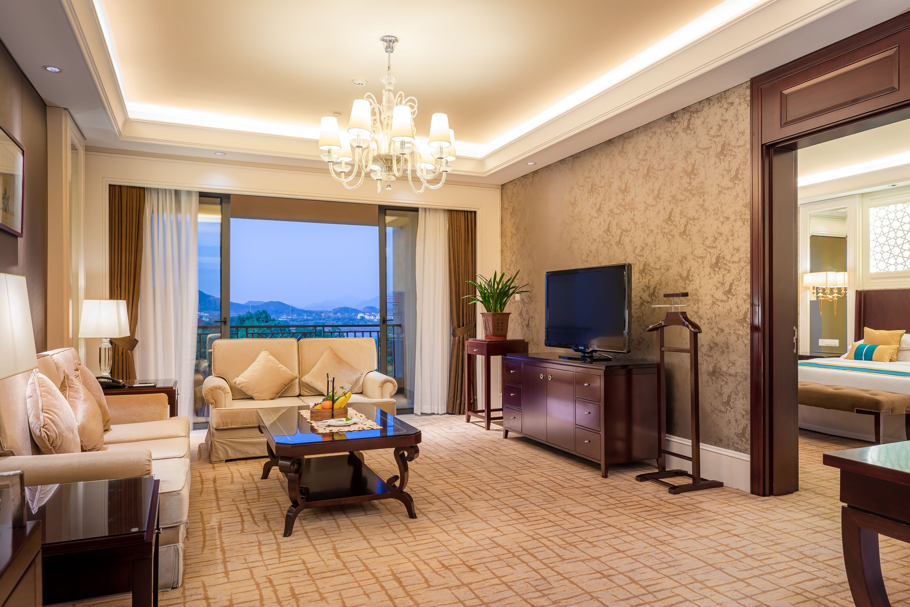 Une chambre d’hôtel avec un canapé, une table basse, une télévision et un balcon offrant une vue.