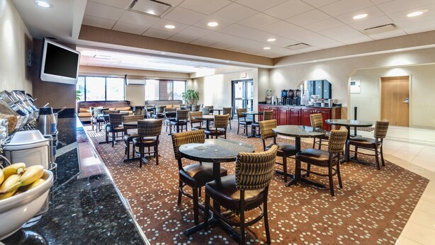 A hotel lobby with multiple seating areas, a coffee station, and a kitchen in the background.
