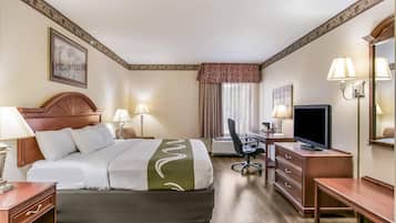 Een hotelkamer met een bed, bureau, televisie en een stoel.
