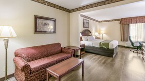 A hotel room with a sofa, a bed, a desk, and a lamp.