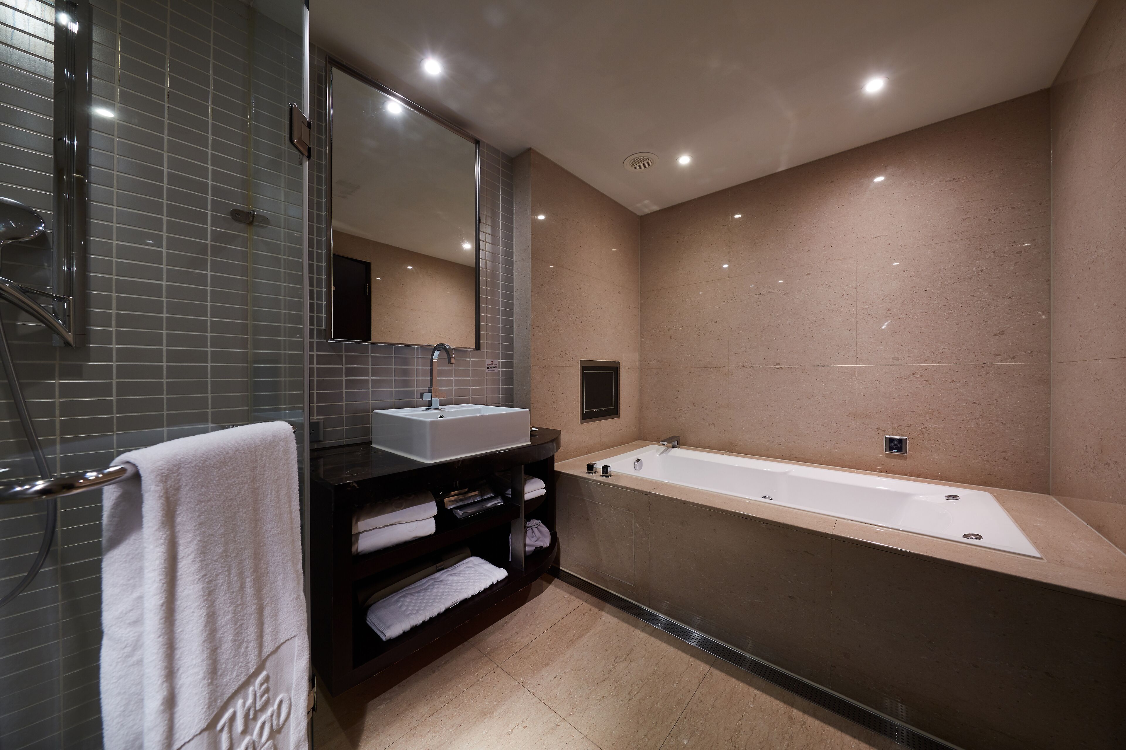 Un baño moderno con una bañera grande, un tocador con lavamanos y un espejo.