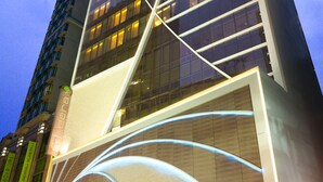 Un immeuble moderne de grande hauteur, doté d’une façade en verre incurvée et de lignes lumineuses qui le distinguent.