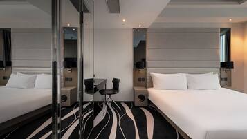 Een hotelkamer met twee bedden, een bureau, stoelen en een grote spiegel.