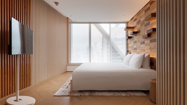 Une chambre moderne dotée d’un grand lit, d’un téléviseur à écran plat et offrant une vue sur la ville.