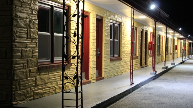 A row of motel rooms with stone walls and red doors. - Driftwood Inn (Chestertown)
