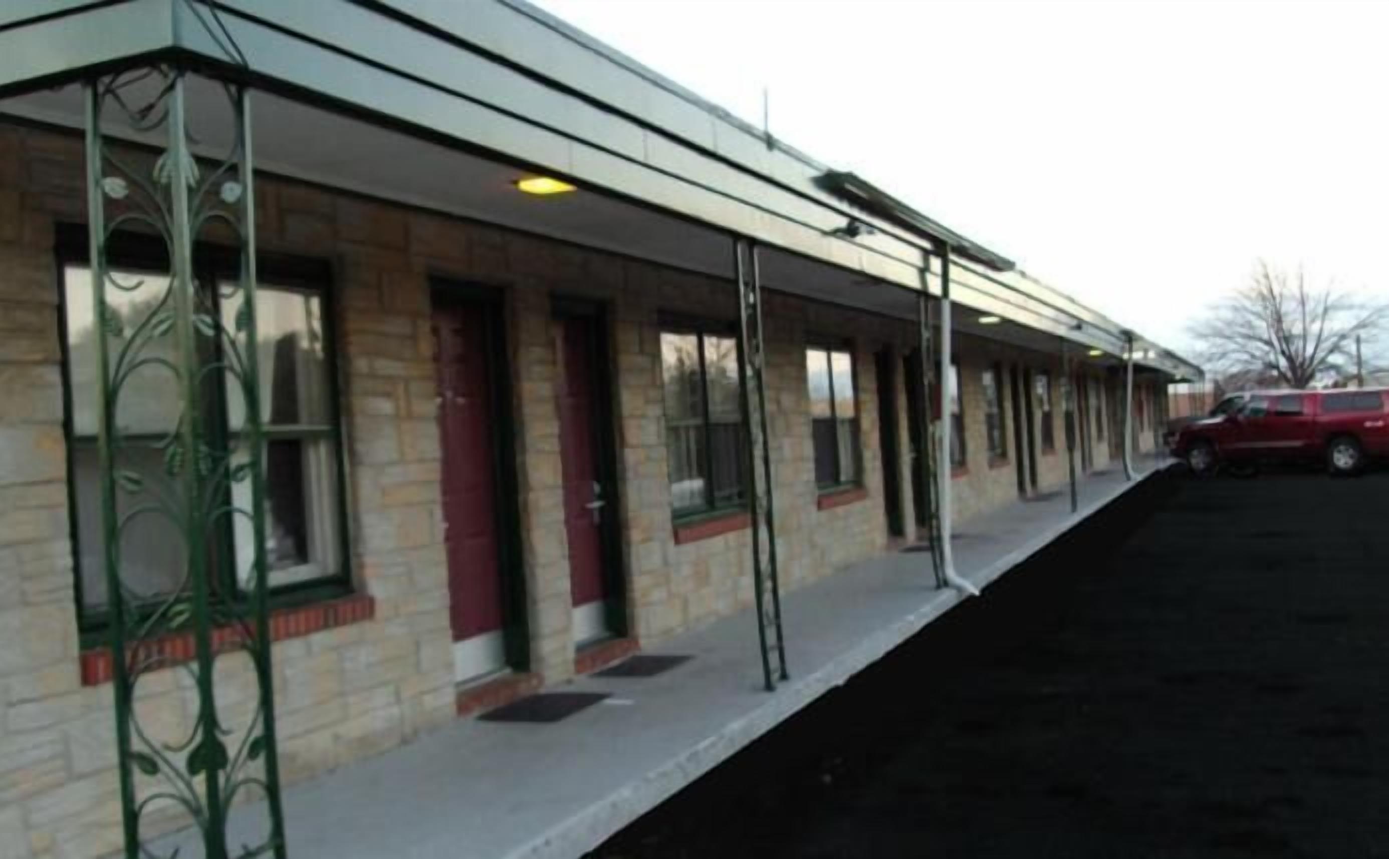 A building with a covered walkway, large windows, and a red car parked outside.