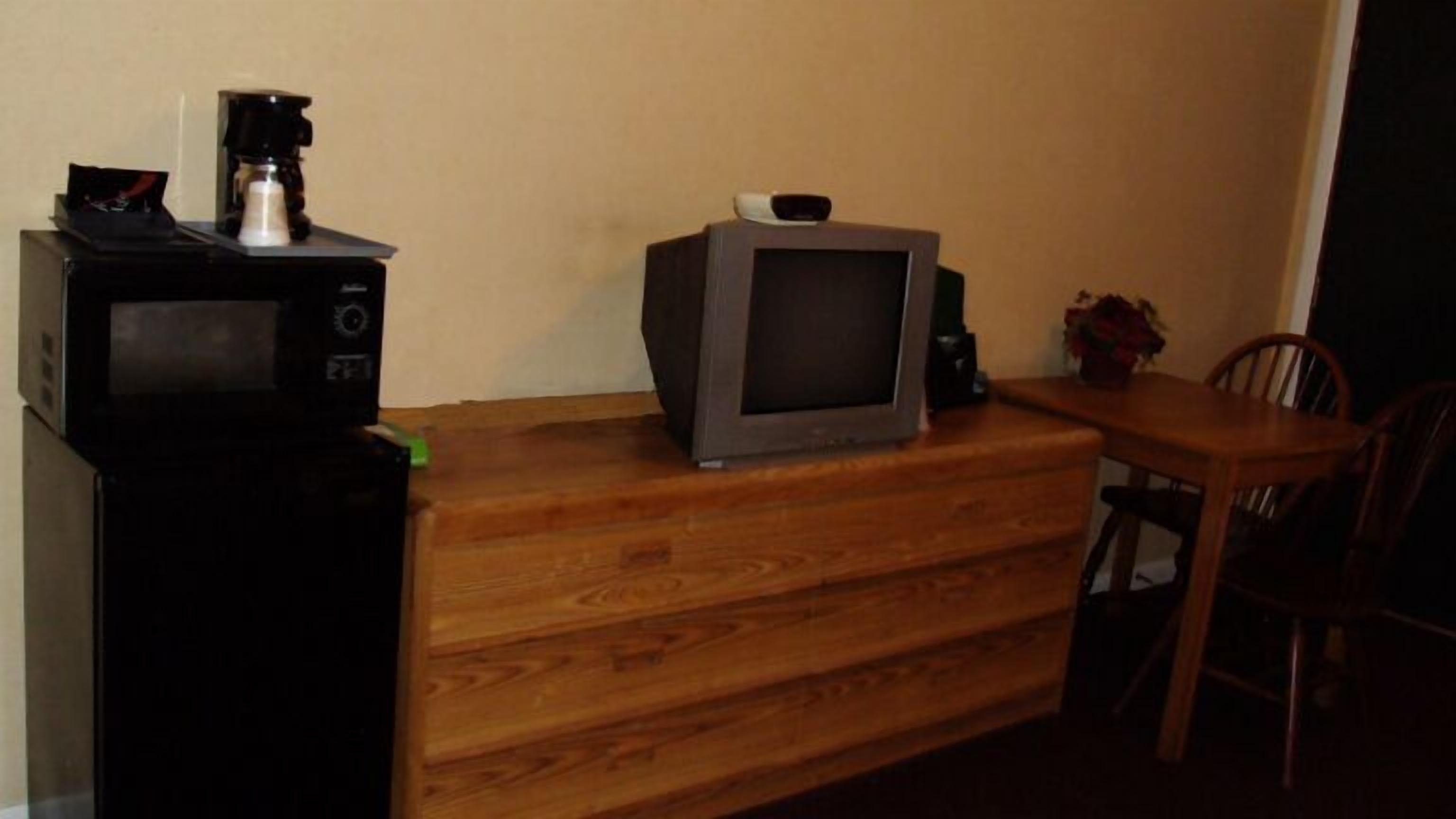 A wooden dresser with a television and a coffee maker on top.