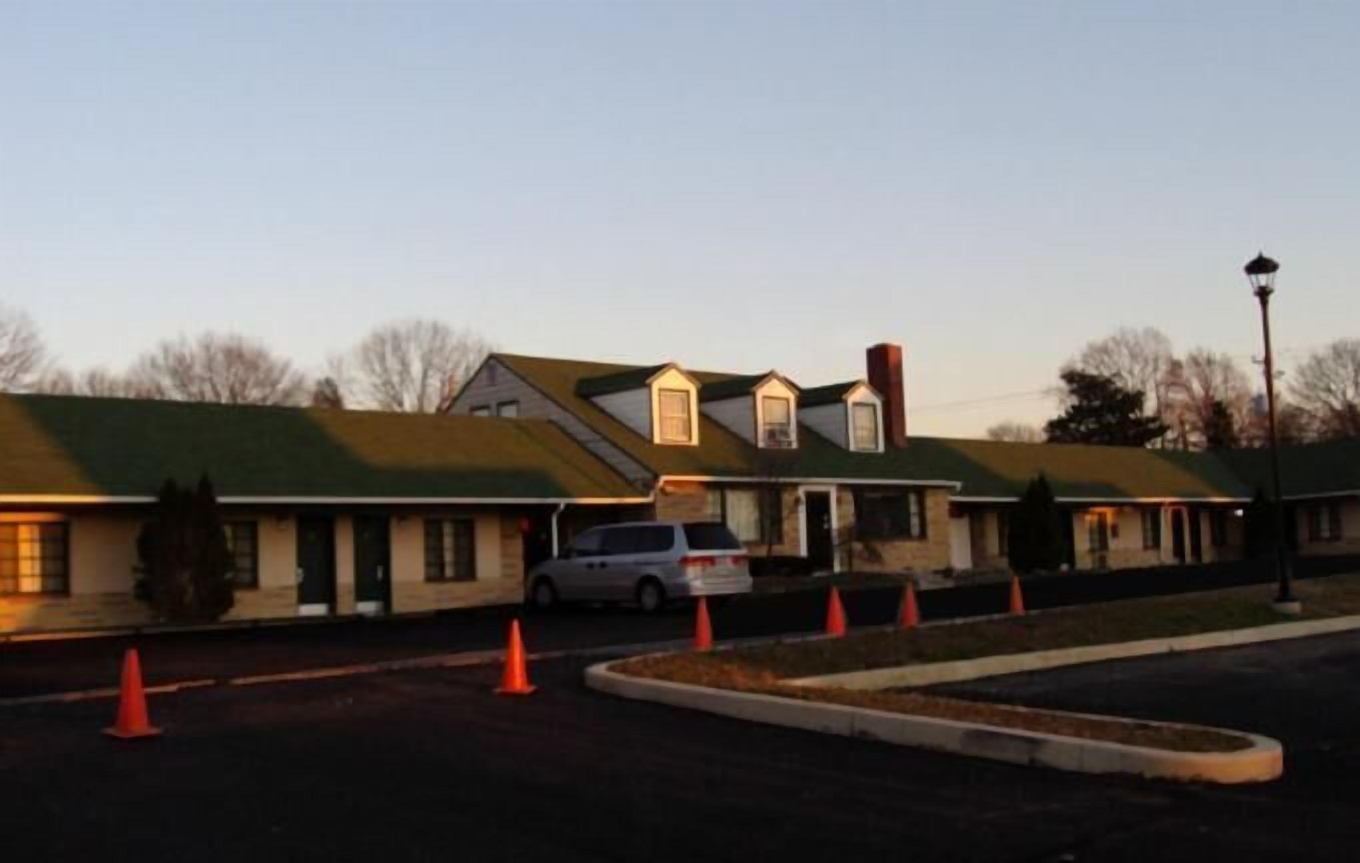 A motel with multiple rooms, a parking lot, and a few orange traffic cones.