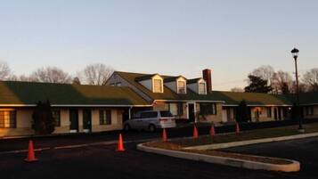 A motel with multiple rooms, a parking lot, and a few orange traffic cones.