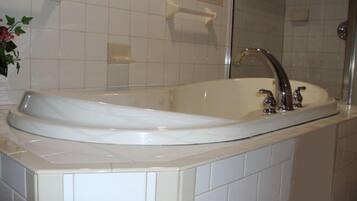 Un baño moderno con una bañera independiente, cabina de ducha con mampara de vidrio y pared con azulejos blancos.