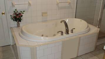 A bathroom with a large bathtub, a toilet, and a sink.